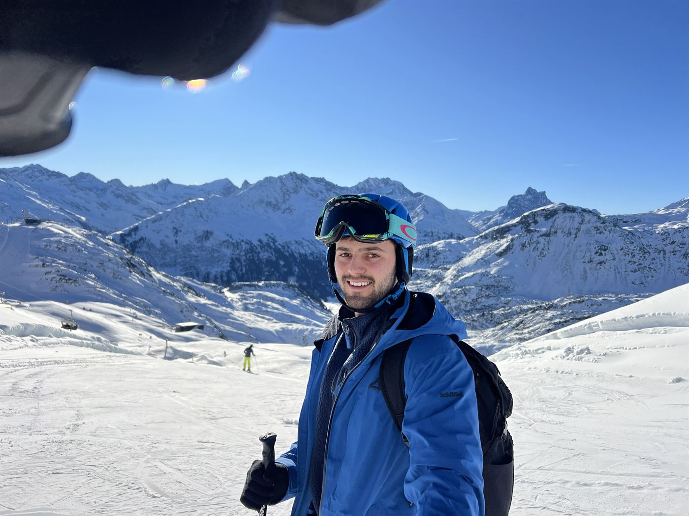 David in ski gear on a groomed run with snow-covered peaks behind