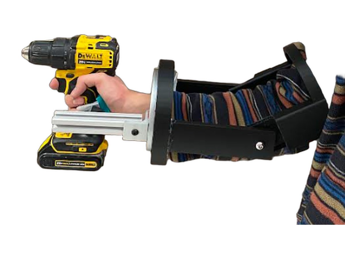 The MVP exoskeleton worn on a forearm: a black shell along the arm, a rotating wrist ring, and an aluminum arm linking it to the cordless drill in the user's hand